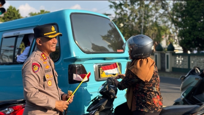 Saat Memberi Pengendara Bendera Merah Putih  AKBP Douglas Tersenyum Manis
