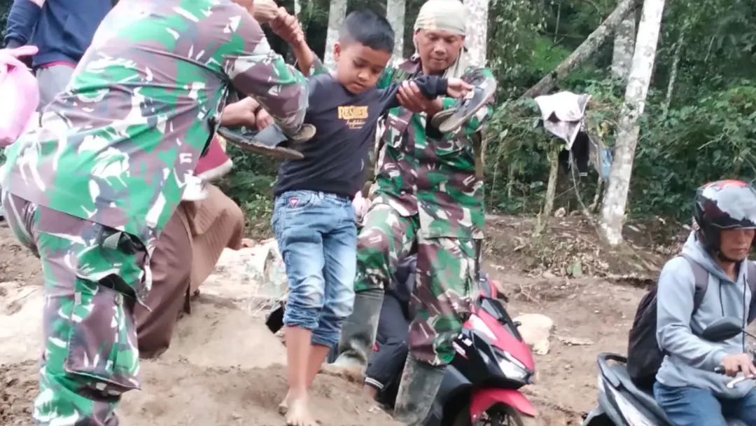 Personel Satgas Penanggulangan Bencana Bantu Penyebrangan Anak-Anak Dan Lansia Di Jembatan Darurat Umah Besi